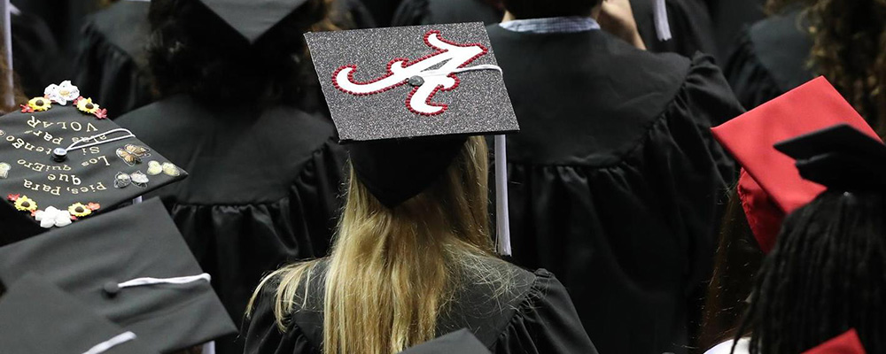 Graduates wearing their caps and gowns with one cap having a script A on the top