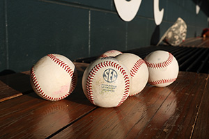 five baseballs sitting on a wooden bench