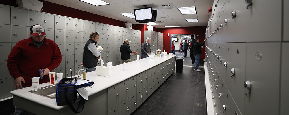 People in the locker room fixing drinks around a central bar